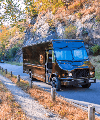 A UPS truck drives up a hill in the woods